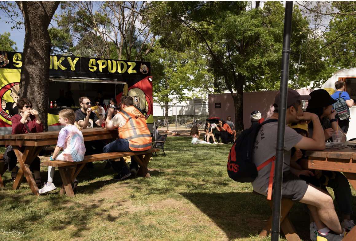 A few groups of people sharing a meal at tables in front of a food truck